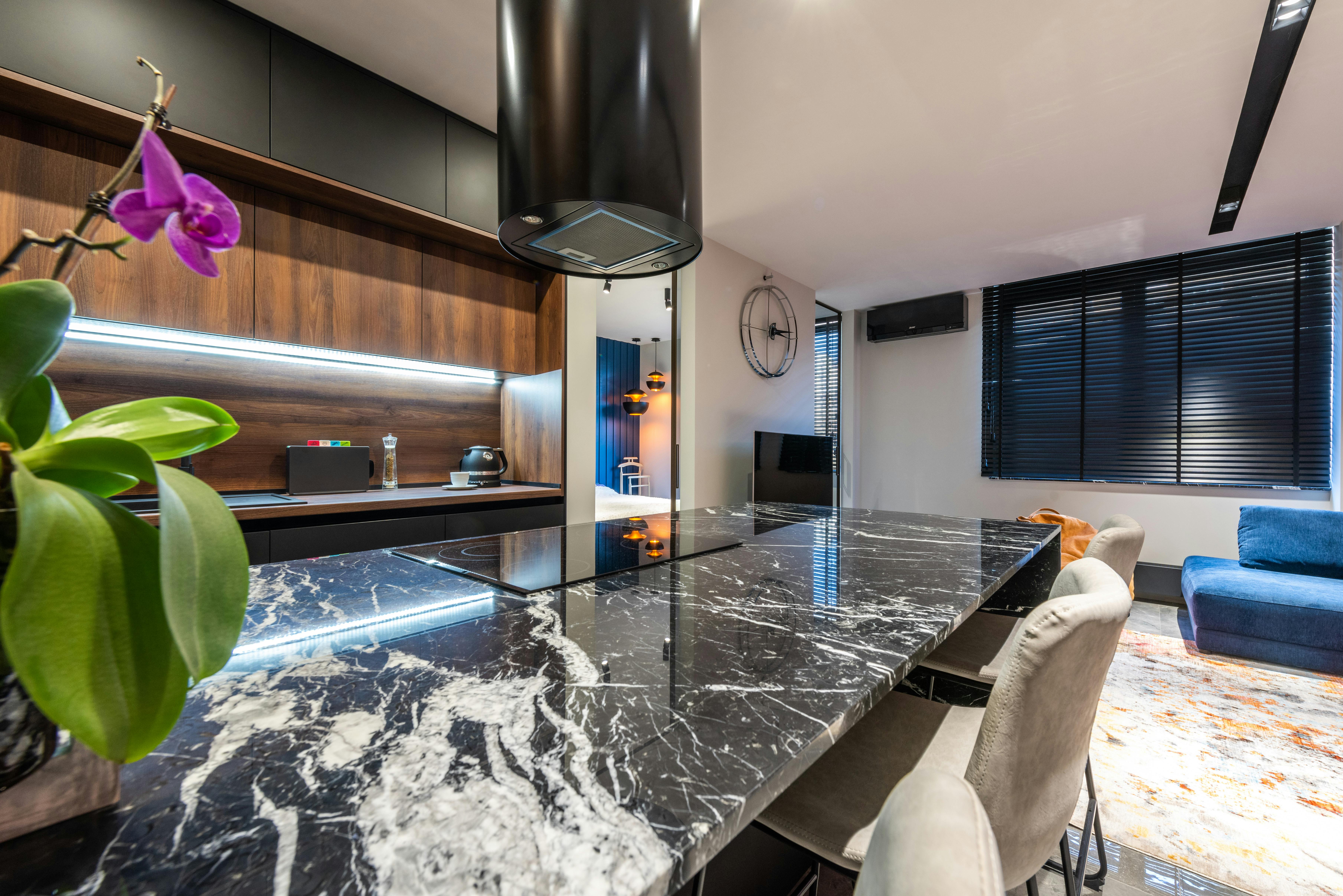 Cocina con isla negra y fondo de madera junto a zona social.
